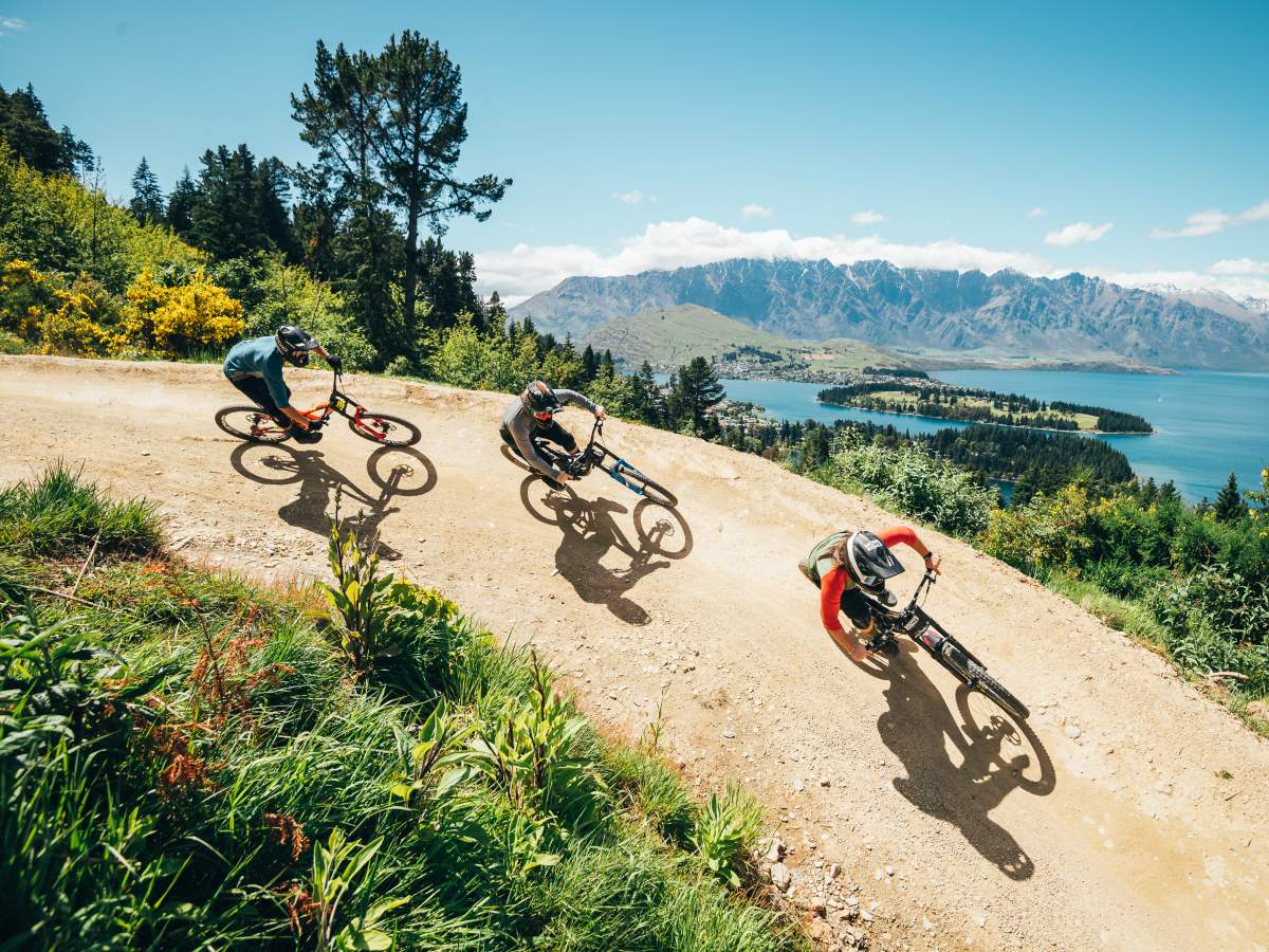 Three riders railing a berm above Queenstown