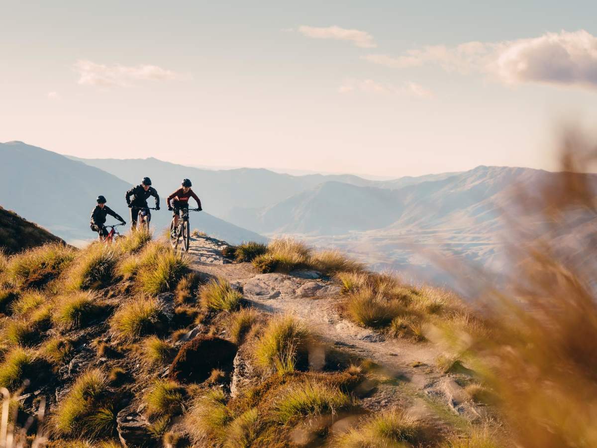 Riders together on a Coronet Peak ridgeline at golden hour